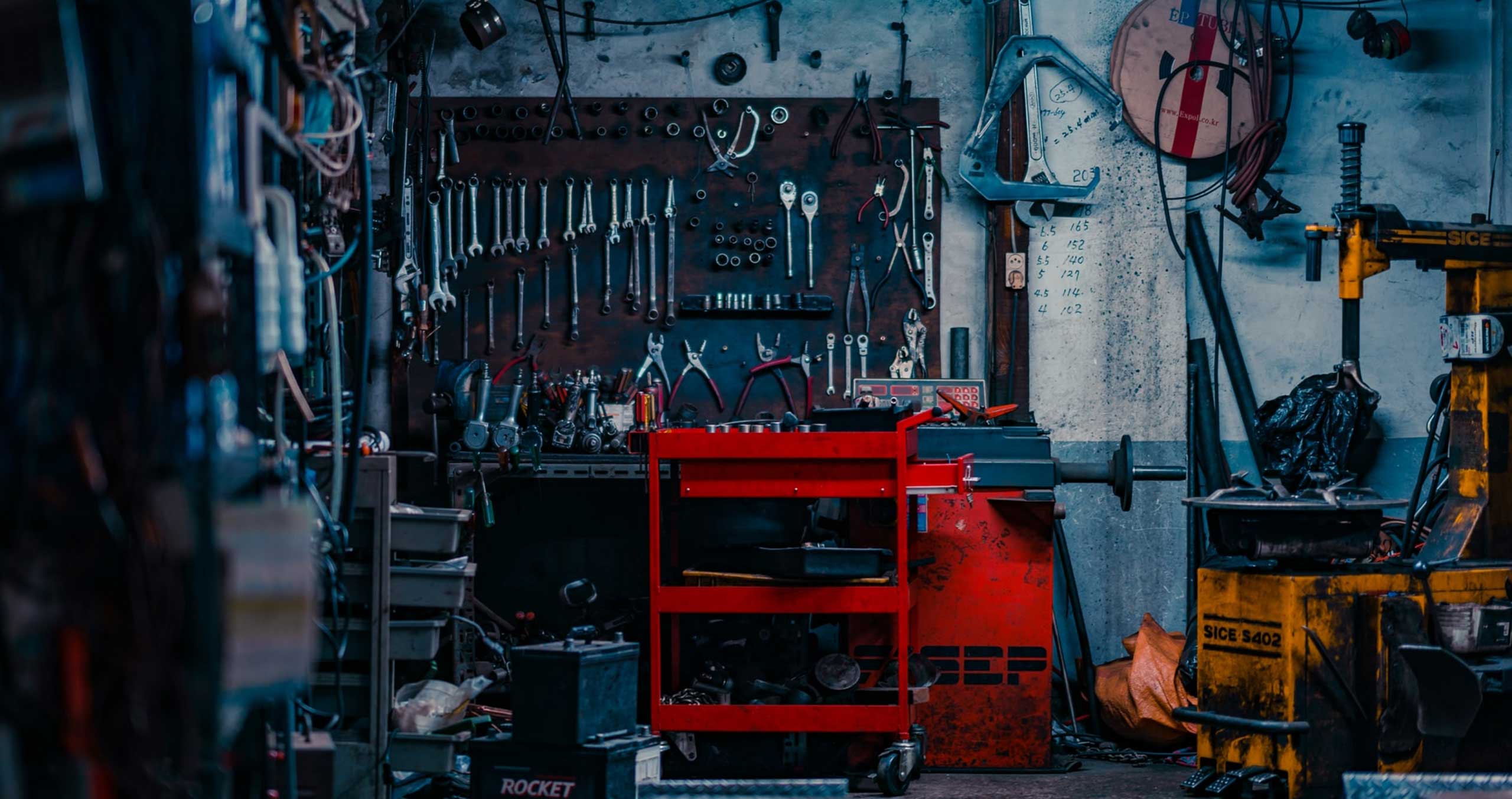 Kuva autokorjaamosta, jossa iso määrä erilaisia työkaluja seinällä
