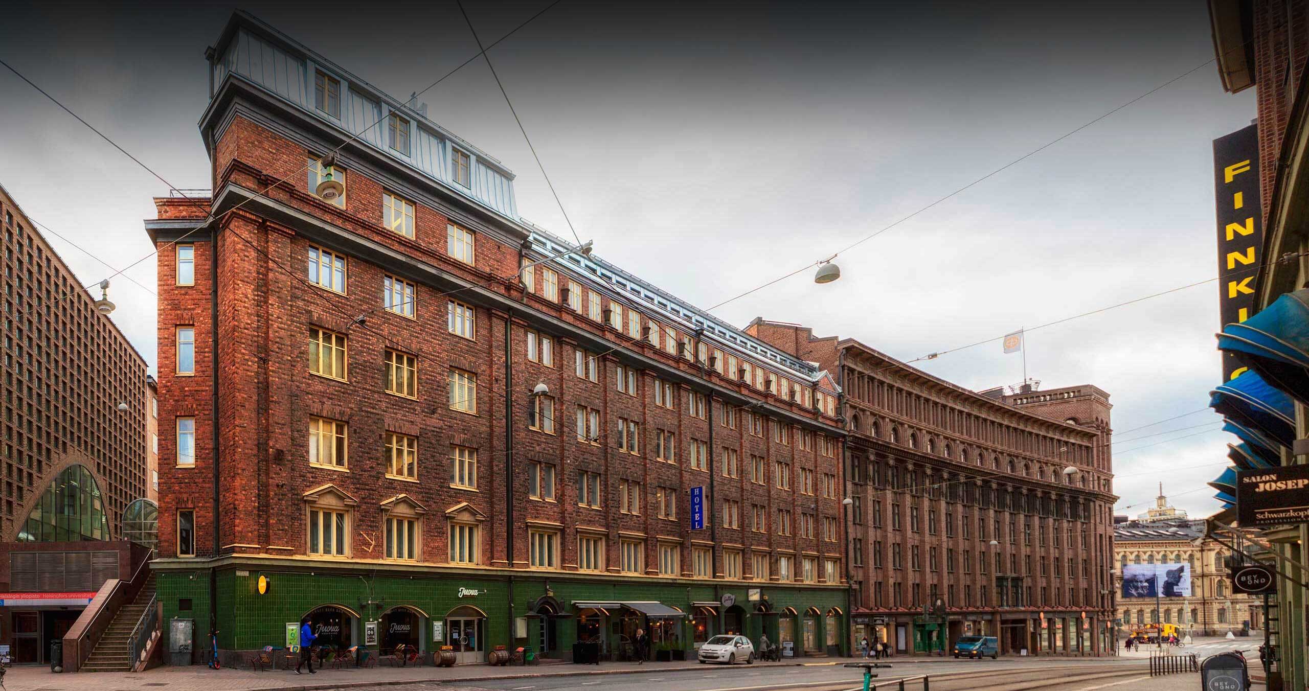 Kuvassa upea klassinen tiilitalo, jossa sijaitsee Suomen Yritysmyynnin päämaja Helsingissä osoitteessa Kaisaniemenkatu 3, 6. kerros.